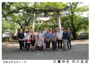 Photo of our tour group at the Taniai Village Shinto temple entry gate donated by Mikao Usui and his brothers in 1925, and with their names inscribed as the donors