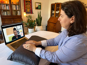 Photo of Gleitia Dushku talking on Zoom to a client and delivering a Virtual Reiki Treatment