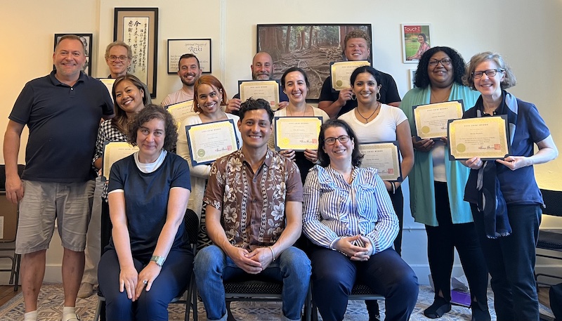 Photo of a Reiki Level 2 class at the NYC Reiki Center with students holding their Reiki Certificates with Master Brian Brunius
