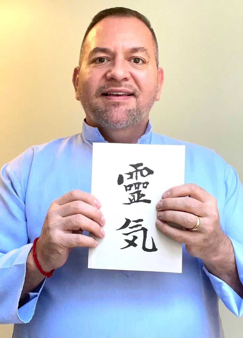 Photo of Brian Brunius holding a copy of "Reiki: The Grey Book" compiled by Alice Takata Furumoto in 1982 from the documents of her mother, Hawayo Takata, and gifted to the first 22 Reiki Masters initiated by Hawayo Takata.